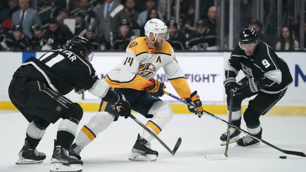 Los Angeles Kings center Anze Kopitar (11) and center Adrian Kempe (9) defend against Nashville Predators defenseman Mattias Ekholm (14) during the third period of an NHL hockey game Tuesday, March 22, 2022, in Los Angeles. (AP Photo/Ashley Landis)