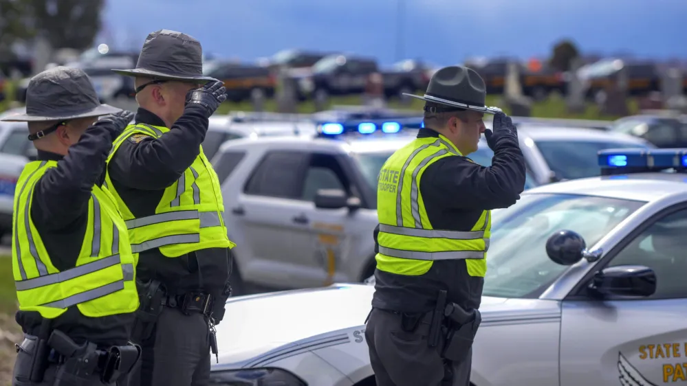 Law enforcement personnel salute during a funeral for Bluffton Police Officer Dominic Francis, Friday, April 8, 2022, in Bluffton, Ohio. Francis was killed in the line of duty during a police chase on March 31. (Richard Parrish/The Lima News via AP)