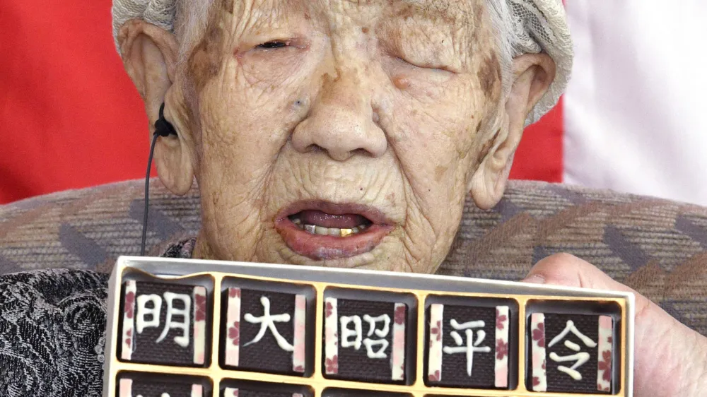 In this Monday, April 1, 2019, photo, Kane Tanaka, who is honored as the world's oldest living person by Guinness World Records at 116, poses with chocolates with era names at a nursing home in Fukuoka, southwestern Japan. Tanaka was born in Meiji era, and will soon experience the fifth era, starting on May 1. The words, from left, read "Meiji, Taisho, Showa, Heisei and Reiwa." (Ryosuke Uematsu/Kyodo News via AP)