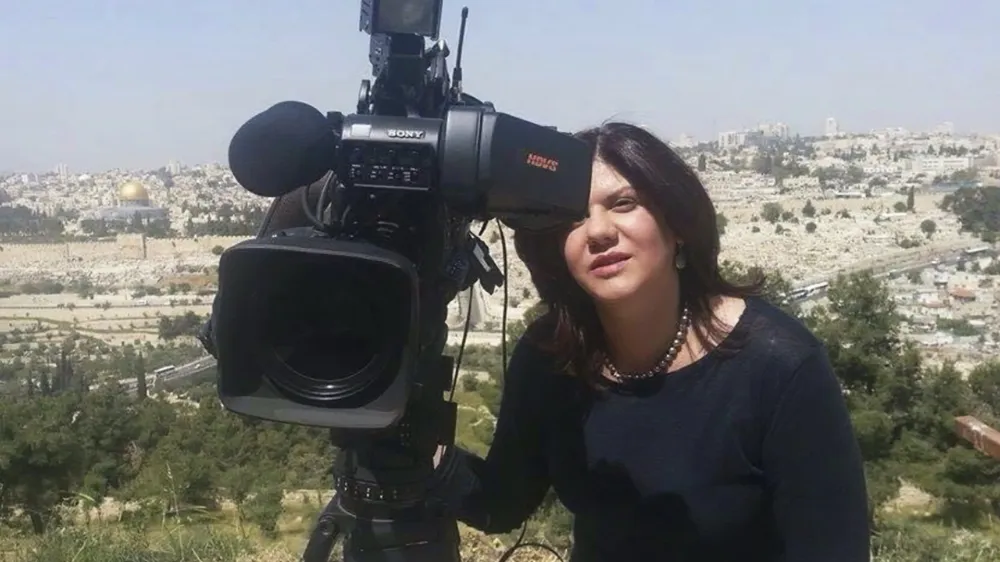 In this undated photo provided by Al Jazeera Media Network, Shireen Abu Akleh, a journalist for Al Jazeera network, stands next to a TV camera in an area where the Dome of the Rock shrine at Al-Aqsa Mosque in the Old City of Jerusalem is seen at left in the background. Abu Akleh, a well-known Palestinian female reporter for the broadcaster's Arabic language channel, was shot and killed while covering an Israeli raid in the occupied West Bank town of Jenin early Wednesday, May 11, 2022. (Al Jazeera Media Network via AP)