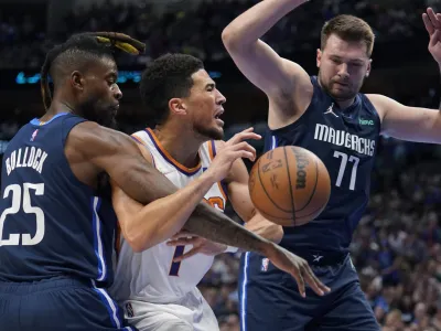 Phoenix Suns guard Devin Booker (1) is fueled by Dallas Mavericks forward Reggie Bullock (25) as guard Luka Doncic (77) looks on during the first half of Game 6 of an NBA basketball second-round playoff series, Thursday, May 12, 2022, in Dallas. (AP Photo/Tony Gutierrez)