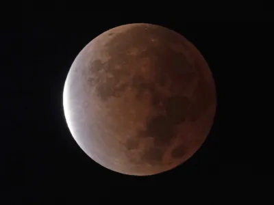 FILE - The earth's shadow covers the full moon during a partial lunar eclipse, Friday, Nov. 19, 2021, in Kansas City, Mo. A total lunar eclipse will grace the night skies this weekend, providing longer than usual thrills for stargazers across North and South America. The celestial action unfolds Sunday, May 15, 2022 night into early Monday morning, with the moon bathed in the reflected red and orange hues of Earth's sunsets and sunrises for about 1 1/2 hours, the longest totality of the decade. It will be the first so-called blood moon in a year.(AP Photo/Charlie Riedel, File)