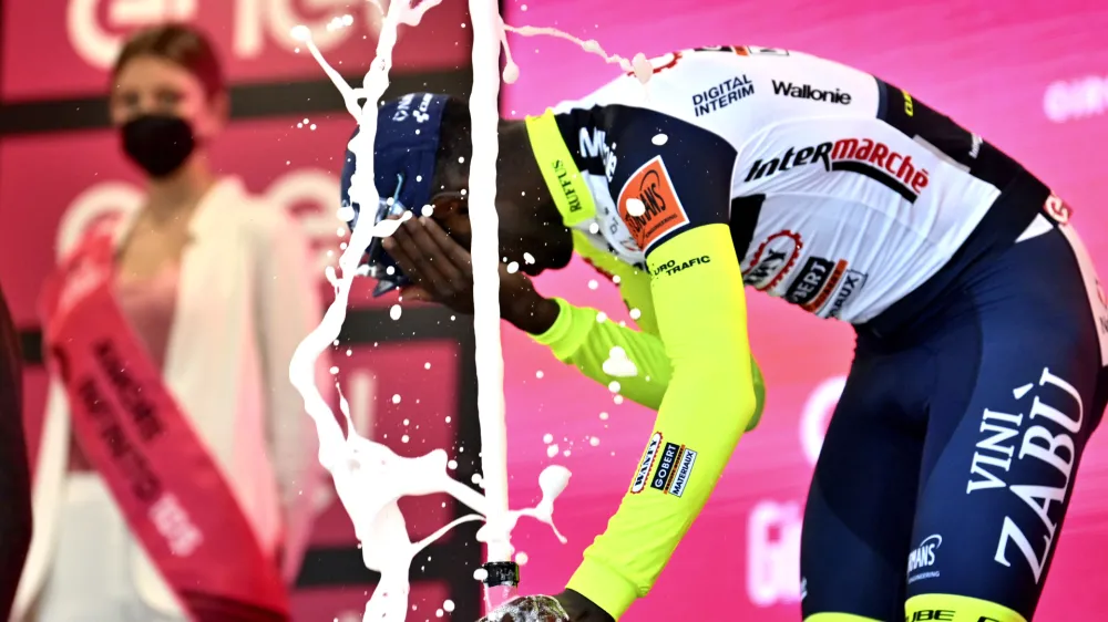 Eritrea's Biniam Girmay touches his eye after spraying sparkling wine on the podium to celebrate winning the 10th stage of the Giro D'Italia cycling race from Pescara to Jesi, Italy, Tuesday, May 17, 2022. Girmay was then taken to a local hospital after getting injured when he popped a champagne cork into his eye during the podium celebration. (Massimo Paolone/LaPresse via AP)