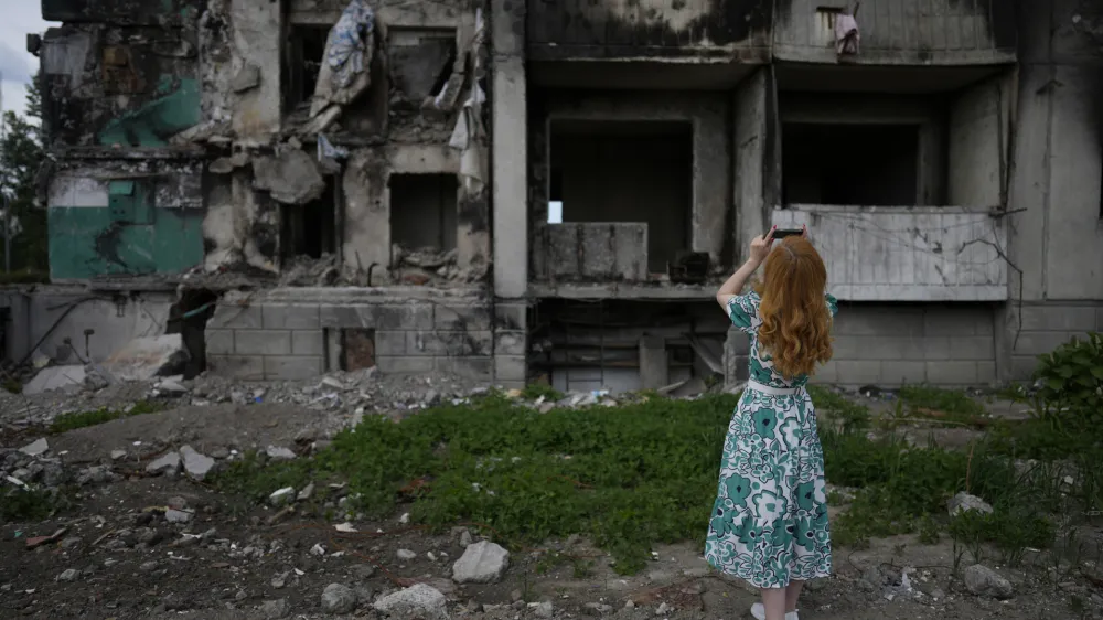 A woman takes pictures of a building destroyed by shelling, in Borodyanka, on the outskirts of Kyiv, Ukraine, Saturday, June 4, 2022. (AP Photo/Natacha Pisarenko)