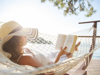Woman in a hammock with book on summer day