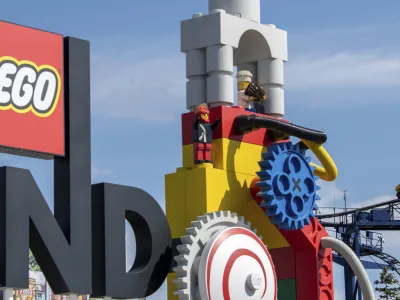 A roller coaster can be seen next to the logo at the entrance to the 'Legoland' amusement park in Guenzburg, southern Germany, Thursday, Aug. 11, 2022. At least 34 people were injured in the accident on a roller coaster at Legoland in Guenzburg, two of them seriously. (Stefan Puchner/dpa via AP)