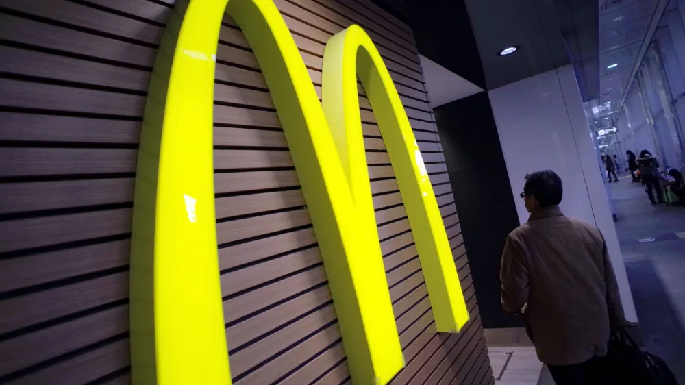 FILE - In this Dec. 17, 2014 file photo, a man walks by a McDonald's logo in front of its restaurant in Tokyo. McDonalds is set to unveil its latest plans to revive its sputtering business on Monday, May 4, 2015. (AP Photo/Eugene Hoshiko, File)