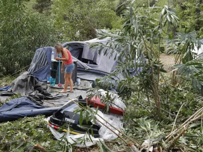 18 August 2022, France, Coggia: A woman packs up the remains of destroyed tents and other items at the Sagone campsite, where a tree fell on a bungalow during a storm, killing one person. Several people have died in violent storms on the French Mediterranean island of Corsica. Photo: Pascal Pochard-Casabianca/AFP/dpa