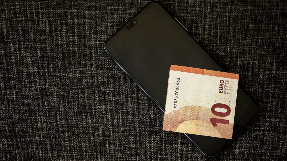 Simbolična fotografija mobilnega telefona in bankovca za 10 evrov.
