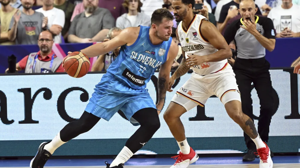 Germany's Nick Weiler-Babb and Slovenia's Luka Doncic, left, fight for the ball during the Eurobasket preliminary round Group B match between Germany and Slovenia in Cologne, Germany, Tuesday, Sept. 6, 2022. (Federico Gambarini/dpa via AP)