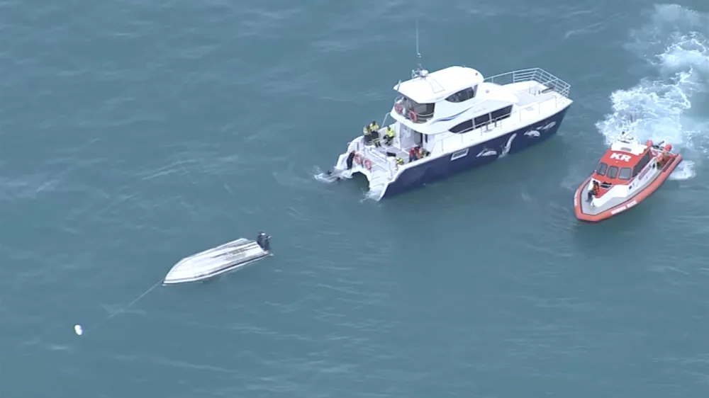 An aerial view shows two rescue boats alongside a capsized boat Saturday, Sept. 10, 2022, Kaikoura, New Zealand. Five people in New Zealand died Saturday after the small charter boat they were aboard capsized, authorities say, in what may have been a collision with a whale. Another six people aboard the boat were rescued. (TVNZ via AP)