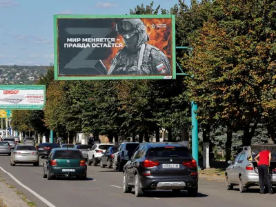 Vehicles drive past advertising boards, including panels displaying pro-Russian slogans, in a street in the course of Russia-Ukraine conflict in Luhansk, Ukraine September 20, 2022. One of the boards reads: "World changes - truth stays. Army of Russia". REUTERS/Alexander Ermochenko