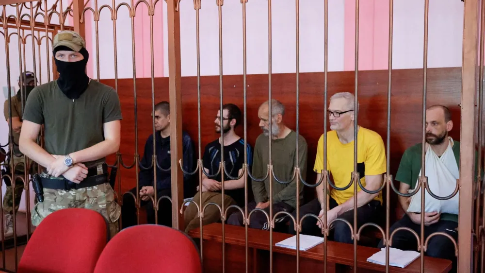 Foreign nationals Vjekoslav Prebeg from Croatia, Dylan Healy from Britain, John Harding from Britain, Mathias Gustafsson from Sweden and Andrew Hill from Britain, who were captured by pro-Russian forces while allegedly fighting for Ukrainian troops during Ukraine-Russia conflict, sit inside a defendants' cage during a court hearing in Donetsk, Ukraine August 15, 2022. REUTERS/Alexander Ermochenko