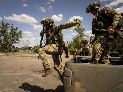 FILE - Ukrainian servicemen of "Fireflies" reconnaissance team jump from the trunk of pickup to take their position at the frontline in Mykolaiv region, Ukraine, Aug. 8, 2022. During the summer, Ukrainian troops launched relentless attacks to reclaim parts of the province, also called Kherson and one of four regions that Russia illegally annexed after sham referendums last month. Ukrainian forces pressing an offensive in the south have zeroed in on Kherson, a provincial capital that has been under Russian control since the early days of the invasion. (AP Photo/Evgeniy Maloletka, File)