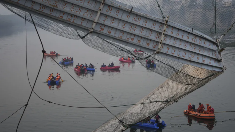 Rescuers on boats search in the Machchu river next to a cable suspension bridge that collapsed in Morbi town of western state Gujarat, India, Monday, Oct. 31, 2022. The century-old cable suspension bridge collapsed into the river Sunday evening, sending hundreds plunging in the water, officials said. (AP Photo/Ajit Solanki)