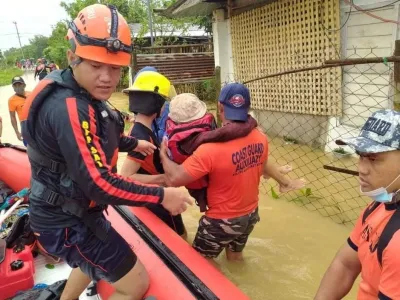 Rescue personnel assist a person onto a rescue boat along a flooded road, after the tropical storm Megi hit in Capiz Province, Philippines April 12, 2022. Philippine Coast Guard/Handout via REUTERS THIS IMAGE HAS BEEN SUPPLIED BY A THIRD PARTY. MANDATORY CREDIT. NO RESALES. NO ARCHIVES