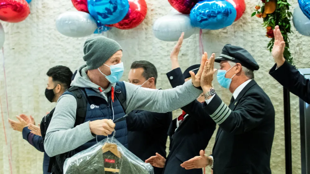 A man gives a high five to the crew members as he exits baggage claim after landing in the British Airways flight at JFK International Airport in New York, U.S., November 8, 2021. REUTERS/Eduardo Munoz