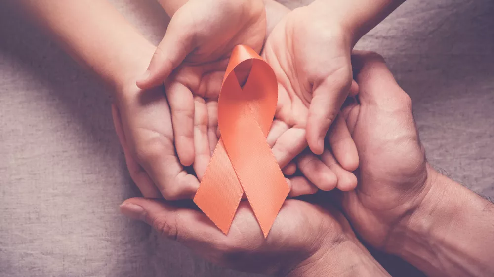 Adult and child hands holding orange Ribbons, Leukemia cancer and Multiple sclerosis, COPD and ADHD awareness, world kidney day