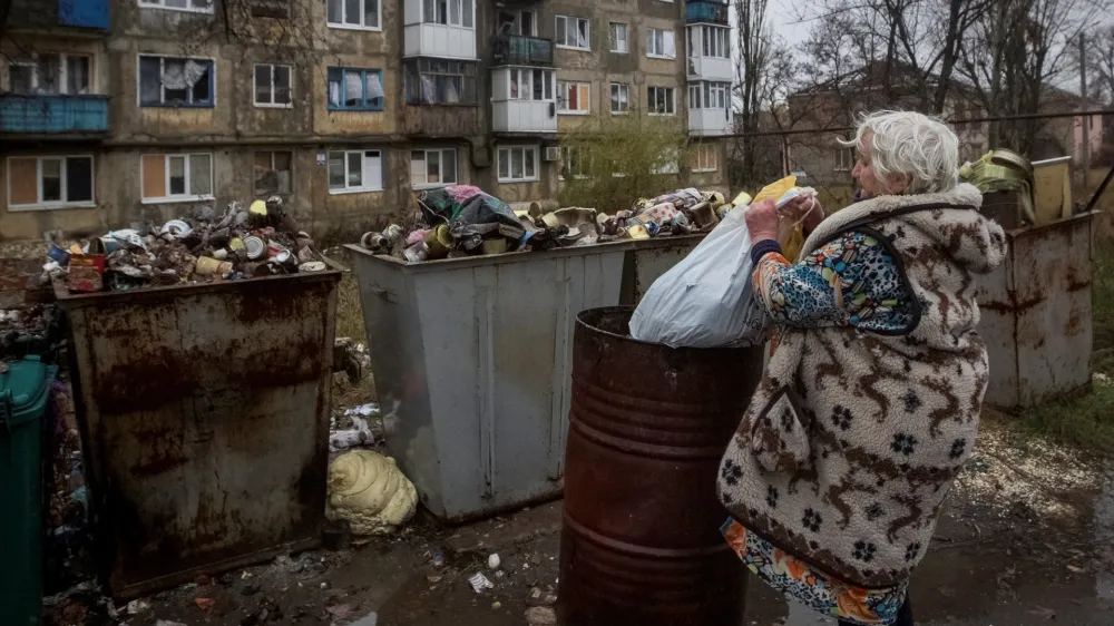 A local resident takes out a trash bag, as Russia's attack in Ukraine continues, in Vuhlidar, Donetsk region, Ukraine, November 19, 2022. REUTERS/Anna Kudriavtseva
