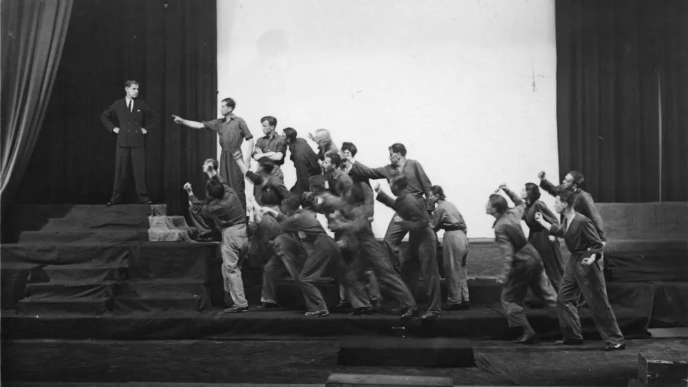 Krstna uprizoritev Delakove dramatizacije Hlapca Jerneja, podnaslovljene &raquo;Igra z narodom: kolektivna drama&laquo;. V avtorjevi režiji in izvedbi Delavskega odra v Ljubljani so jo premierno uprizorili 23. maja 1932. Ikonoteka SLOGI &ndash; Gledali&scaron;ki muzej.