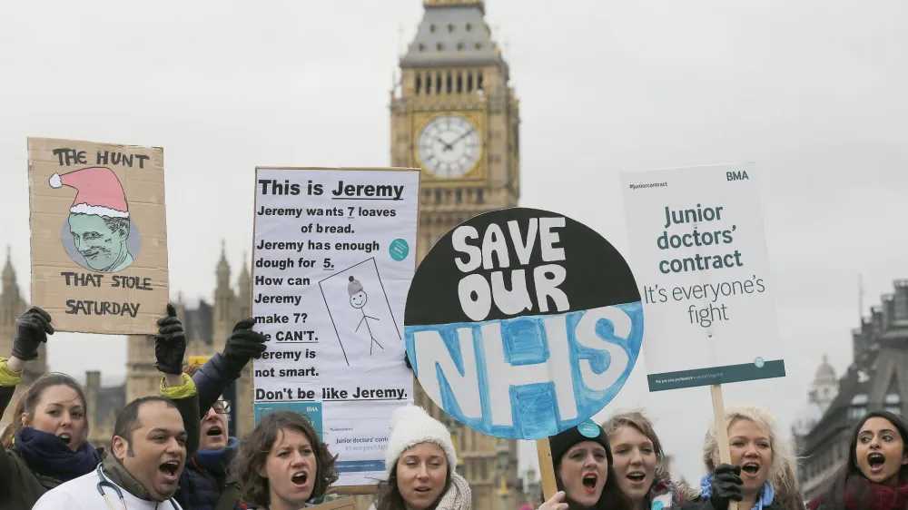 Junior National Health Service (NHS) doctors wave placards referring to British Conservative Party Secretary of State for Health, Jeremy Hunt, during a protest outside St Thomas Hospital in London, Wednesday, Feb. 10, 2016, backdropped by the Houses of Parliament and Big Ben's clock tower. Thousands of junior doctors have walked off the job in England in a dispute over pay and working conditions. (AP Photo/Frank Augstein)