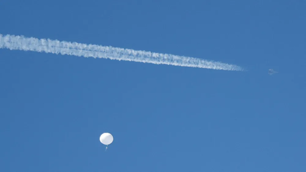 FILE PHOTO: A jet flies by a suspected Chinese spy balloon as it floats off the coast in Surfside Beach, South Carolina, U.S. February 4, 2023. REUTERS/Randall Hill/File Photo