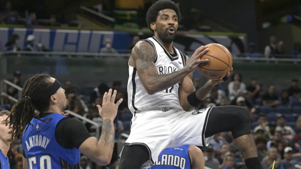 Brooklyn Nets guard Kyrie Irving (11) looks to pass after driving to the basket as Orlando Magic guard Cole Anthony (50) defends during the first half of an NBA basketball game Tuesday, March 15, 2022, in Orlando, Fla. (AP Photo/Phelan M. Ebenhack)