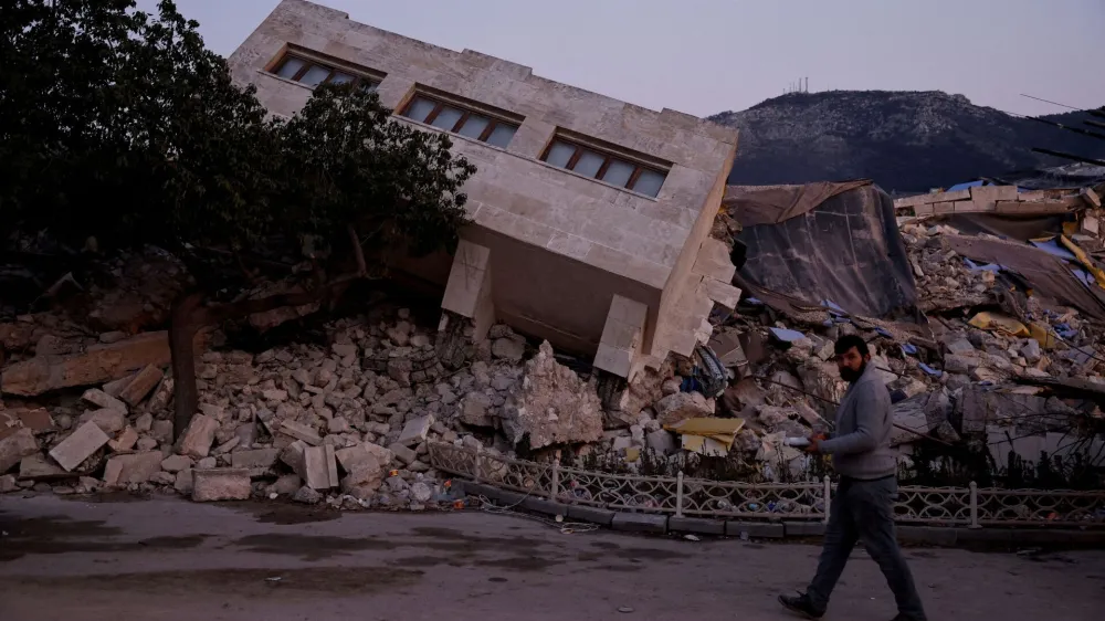 FILE PHOTO: FILE PHOTO: A man walks by a collapsed building and rubble, in the aftermath of a deadly earthquake, in Antakya, Hatay province, Turkey, February 21, 2023. REUTERS/Clodagh Kilcoyne/File Photo/File Photo