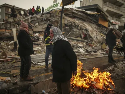 FILE - People warm themselves next to a collapsed building in Malatya, Turkey, on Feb. 7, 2023. A magnitude 5.6 earthquake shook southern Turkey on Monday Feb. 27, 2023 three weeks after a catastrophic temblor devastated the region, causing some already damaged buildings to collapse and killing at least one person, the country's disaster management agency, AFAD, said. (AP Photo/Emrah Gurel, File)