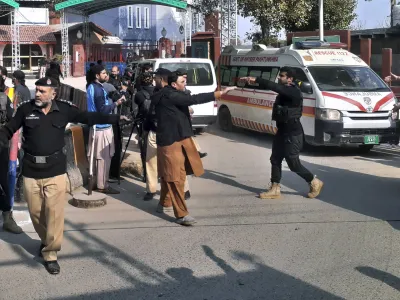Police officers clear the way for ambulances leaving after carrying wounding people from bomb explosion site, at the main entry gate of police offices, in Peshawar, Pakistan, Monday, Jan. 30, 2023. A powerful bomb went off Monday near a mosque and police offices in the northwestern Pakistani city of Peshawar, killing at least a few people and wounding some 70 worshippers, police and government officials said. (AP Photo/Muhammad Sajjad)