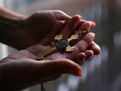 FILE - Christine Zuba holds the cross she wears when serving as a eucharistic minister at Saints Peter and Paul Catholic Church at her home in Blackwood, New Jersey, on Monday, Feb. 14, 2022. After coming out as transgender at age 58, Zuba, a lifelong Catholic, was welcomed into the parish. On Monday, March 20, 2023, United States Catholic bishops have issued guidelines that seek to stop Catholic hospitals from providing gender transition care, a move LGBTQ advocates say could harm the physical and emotional health of transgender people within the church. (AP Photo/Jessie Wardarski)