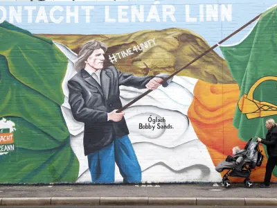 A woman walks past an Irish republican mural in West Belfast, Northern Ireland, Tuesday, March 28, 2023. British intelligence (MI5) raised the Northern Ireland terrorism threat level Tuesday from substantial to severe meaning an attack is highly likely by dissident Irish Republican's. (AP Photo/Peter Morrison)