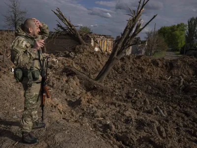 A Ukrainian serviceman inspects a site after an airstrike by Russian forces in Bahmut, Ukraine, Tuesday, May 10, 2022. (AP Photo/Evgeniy Maloletka)