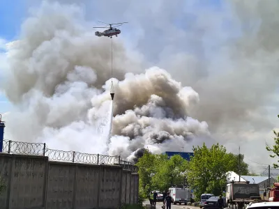 A helicopter extinguishes a fire at a warehouse of tires intended for destruction, in an industrial area district of Lyubertsy district outside Moscow, Russia, Friday, May 12, 2023. The area of the fire was about 2.5 thousand square meters. (Denis Voronin/Moscow News Agency via AP)