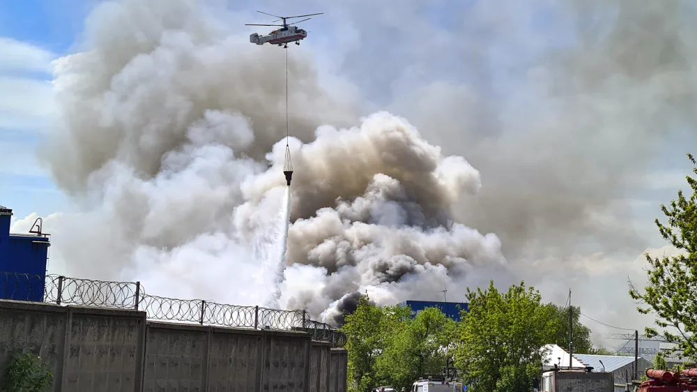 A helicopter extinguishes a fire at a warehouse of tires intended for destruction, in an industrial area district of Lyubertsy district outside Moscow, Russia, Friday, May 12, 2023. The area of the fire was about 2.5 thousand square meters. (Denis Voronin/Moscow News Agency via AP)
