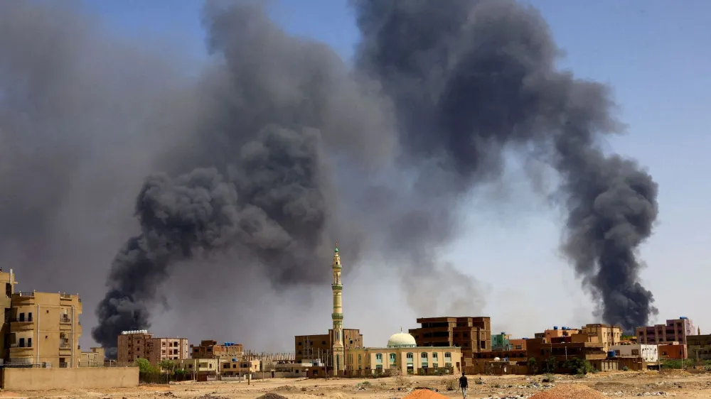 FILE PHOTO: A man walks while smoke rises above buildings after aerial bombardment, during clashes between the paramilitary Rapid Support Forces and the army in Khartoum North, Sudan, May 1, 2023. REUTERS/Mohamed Nureldin Abdallah//File Photo