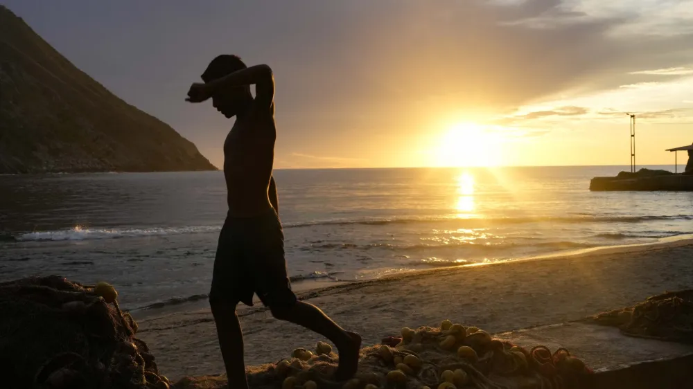 A youth walks on the seaside during sunset in Chuao, Aragua state, Venezuela, Tuesday, June 6, 2023. (AP Photo/Matias Delacroix)