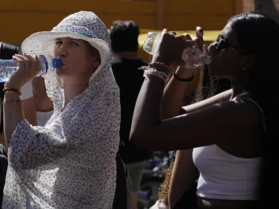 Tourists sips cold water as they shelter from a hot sunny afternoon near the Rome's Colosseum, Wednesday, July 5, 2023. According to weather forecasts temperatures are expected to rise on the upcoming week end reaching in some part of the country 45 Celsius degrees (113 Fahrenheit). (AP Photo/Gregorio Borgia)