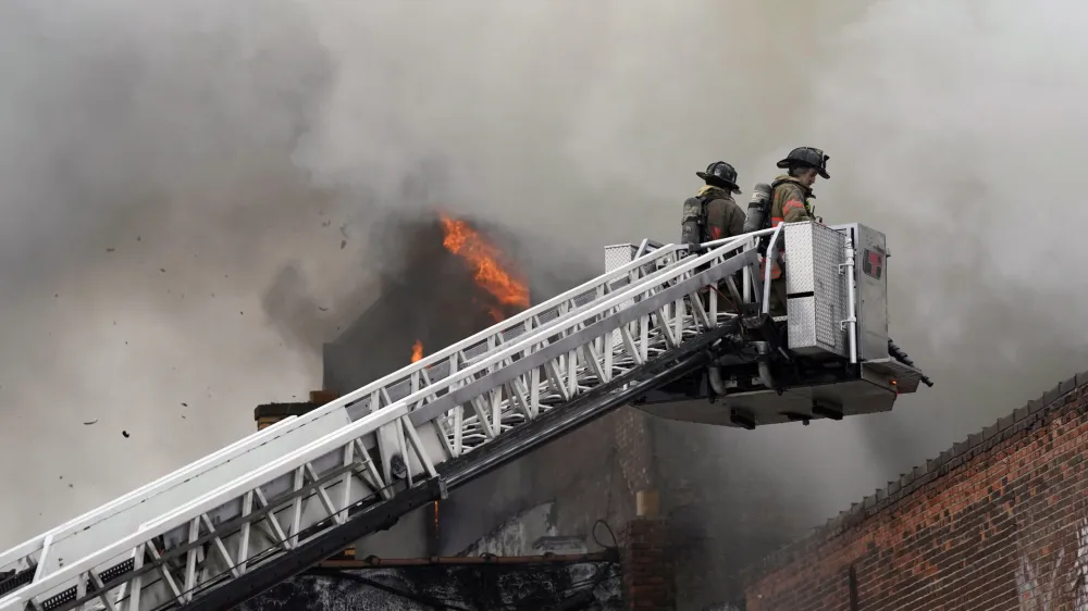 FILE - Buffalo firefighters adjust their approach from above at a massive blaze that claimed the life of Buffalo Firefighter Jason Arno on March 1, 2023, in Buffalo, N.Y. The explosive fire in a Buffalo costume shop where a firefighter became trapped and died has been ruled accidental and no criminal charges will be filed, a prosecutor said Thursday, July 6, 2023. (Derek Gee/The Buffalo News via AP, File)