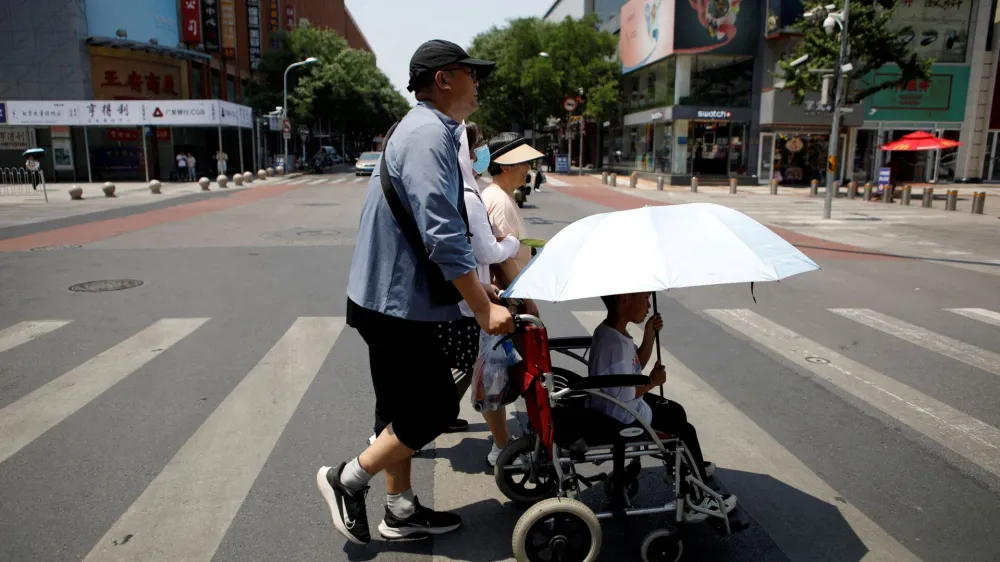 FILE PHOTO: Pedestrians cross a road on a hot day amid an orange alert for heatwave, in Beijing, China June 16, 2023. REUTERS/Florence Lo/File Photo