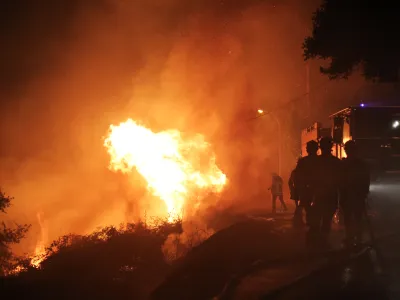 Firefighters spray water as they try to douse a fire near the village of Biguglia, Corsica island, France, Tuesday, July 25, 2017. Hundreds of firefighters are battling blazes fanned by high winds in more than a dozen zones in the Riviera region of southern France. (AP Photo/Raphael Poletti)