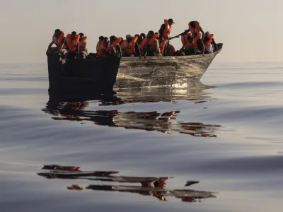 FILE - Migrants with life jackets provided by volunteers of the Ocean Viking, a migrant search and rescue ship run by NGOs SOS Mediterranee and the International Federation of Red Cross (IFCR), sail in a wooden boat as they are being rescued some 26 nautical miles&nbsp;south of the Italian Lampedusa island in the Mediterranean sea,&nbsp;on Aug. 27,&nbsp;2022. The U.N. human rights chief is appealing to governments to do more to help migrants and asylum-seekers after a "steep increase" in the numbers making risky attempts to cross the central Mediterranean to Europe. (AP Photo/Jeremias Gonzalez, File)