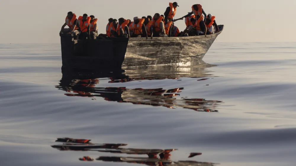 FILE - Migrants with life jackets provided by volunteers of the Ocean Viking, a migrant search and rescue ship run by NGOs SOS Mediterranee and the International Federation of Red Cross (IFCR), sail in a wooden boat as they are being rescued some 26 nautical miles&nbsp;south of the Italian Lampedusa island in the Mediterranean sea,&nbsp;on Aug. 27,&nbsp;2022. The U.N. human rights chief is appealing to governments to do more to help migrants and asylum-seekers after a "steep increase" in the numbers making risky attempts to cross the central Mediterranean to Europe. (AP Photo/Jeremias Gonzalez, File)