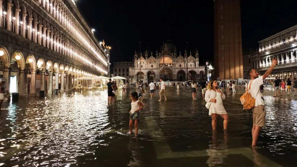 Tourists walk through flooded St Mark's Square after unusually high water levels in Venice, Italy, August 1, 2023. REUTERS/Manuel Silvestri