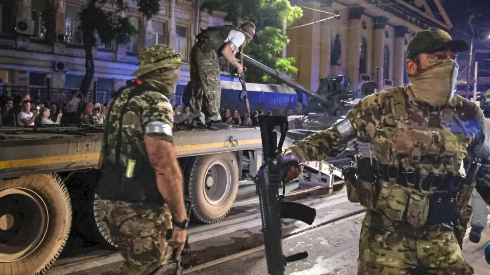 Members of the Wagner Group military company guard an area as other load their tank onto a truck on a street in Rostov-on-Don, Russia, Saturday, June 24, 2023, prior to leaving an area at the headquarters of the Southern Military District. Kremlin spokesman Dmitry Peskov said that Yevgeny Prigozhin's troops who joined him in the uprising will not face prosecution and those who did not will be offered contracts by the Defense Ministry. After the deal was reached Saturday, Prigozhin ordered his troops to halt their march on Moscow and retreat to field camps in Ukraine, where they have been fighting alongside Russian troops. (Vasily Deryugin, Kommersant Publishing House via AP)