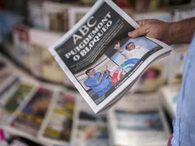 FILE - A man picks up a newspaper with pictures of Spain's Prime Minister and Socialist Workers' Party Pedro Sanchez, left, and Alberto Feijoo, leader of the mainstream conservative Popular Party of the Spain's general election celebrated yesterday in Madrid, Spain, on July 24, 2023. King Felipe VI began consultations with leaders of Spain's political parties Monday Aug. 21, 2023 to see which one has the best chance to form a government following an inconclusive national election last month. (AP Photo/Manu Fernandez, File)