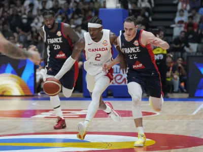 Canada guard Shai Gilgeous-Alexander (2) passes around France forward Terry Tarpey (22) during the Basketball World Cup group H match between France and Canada at the Indonesia Arena stadium in Jakarta, Indonesia, Friday, Aug. 25, 2023. (AP Photo/Dita Alangkara)