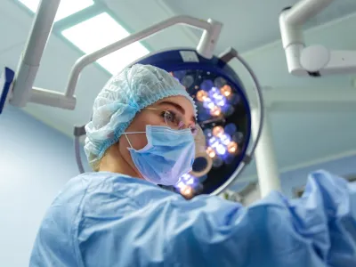 Female Doctor in Surgery Operating Hospital Room. Surgeon medic in protective work wear gloves, mask and cap.