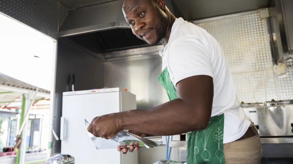 Kuhar in nutricionist Mike Dayo iz Nigerije, ki v Sloveniji živi že 17 let, v kulinaričnem tovornjaku pripravlja jedi iz zahodne Afrike.&nbsp;