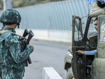Sergey Astsetryan, an ethnic Armenian resident of Nagorno-Karabakh, right, says goodbye to Azerbaijani border guard servicemen after they checked his Soviet-made vehicle at the Lachin checkpoint on the way from Nagorno-Karabakh to Armenia, in Azerbaijan, Sunday, Oct. 1, 2023. Astsetrayn was one of the last residents of Nagorno-Karabakh to drive out of the region in his own vehicle as part of a grueling weeklong exodus of over 100,000 people &mdash; more than 80% of the residents &mdash; after Azerbaijan reclaimed the area in a lightning military operation. (AP Photo/Aziz Karimov)